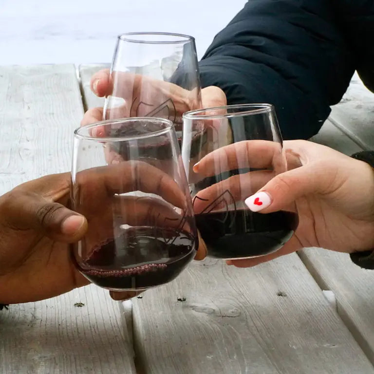 Three people cheers-ing glasses at a picnic table