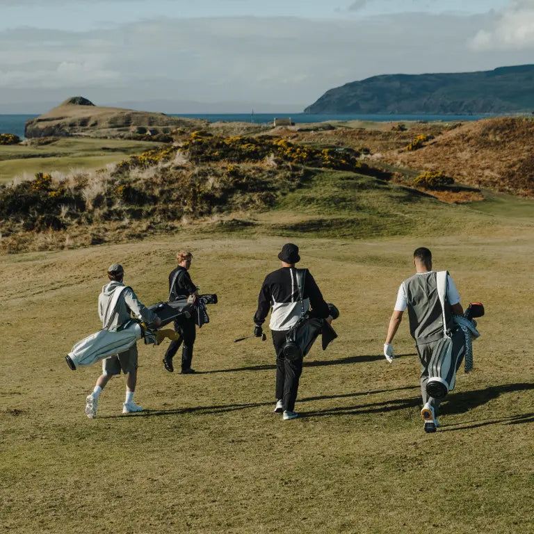 Four men with golf clubs walking on a golf course