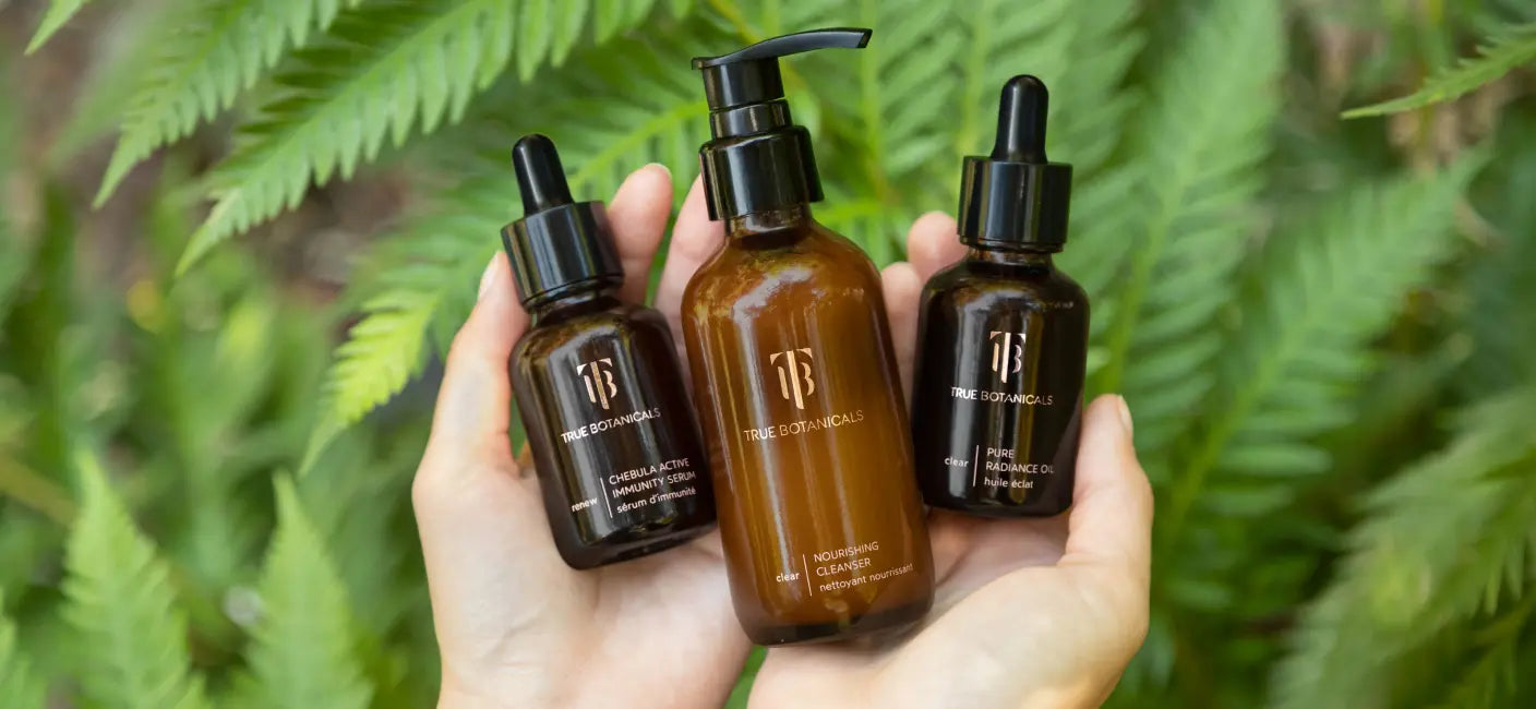 A hand holding True Botanical products outdoors